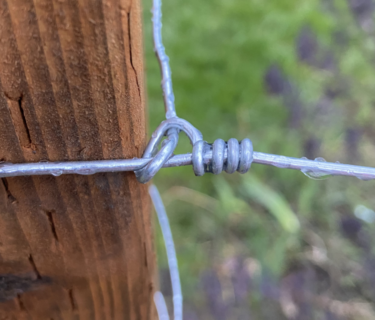 A termination knot tied in high-tensile wire wrapped around a fence post